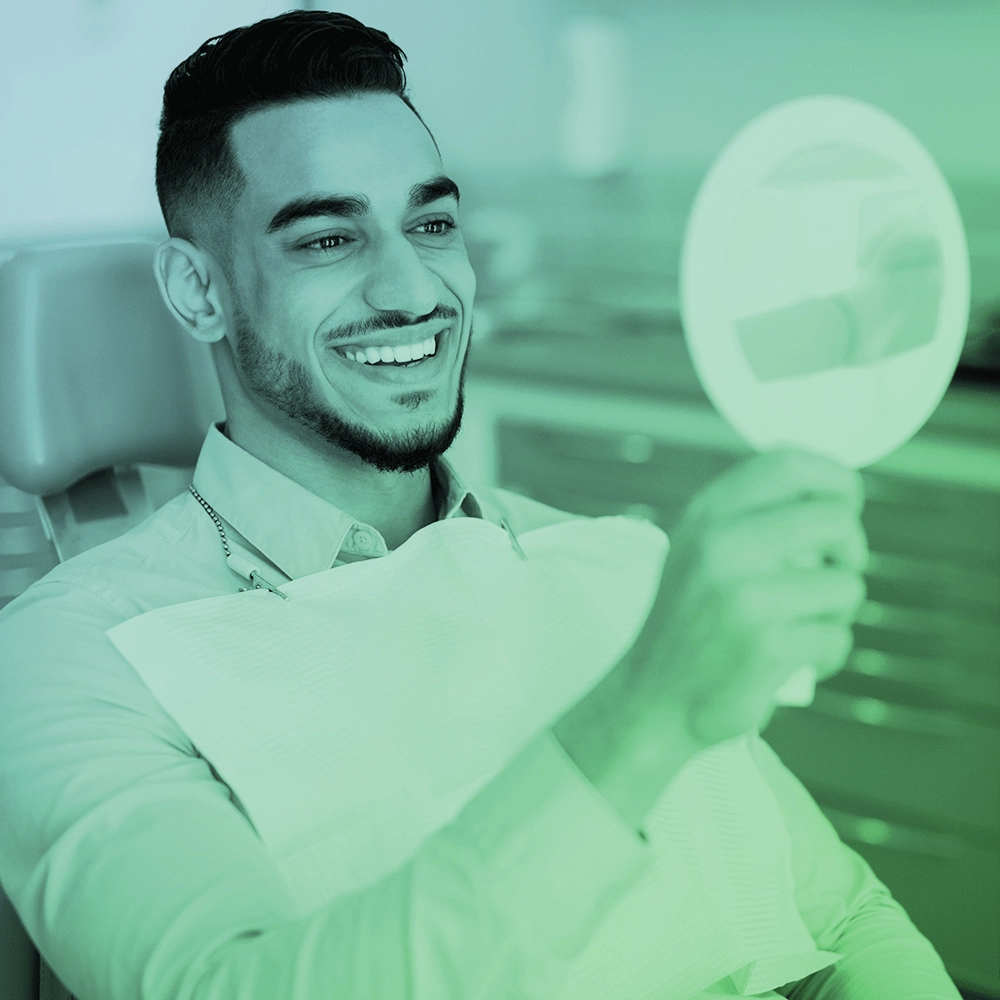 A man at the dentist looking at himself in the mirror.