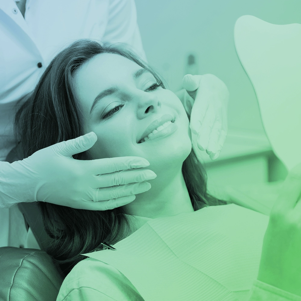 A woman at the dentist looking at herself in the mirror.